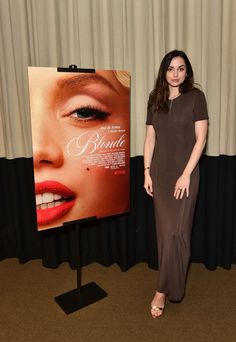 a woman standing in front of a poster