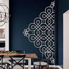 a dining room with a table and chairs in front of a blue wall that has an intricate design on it