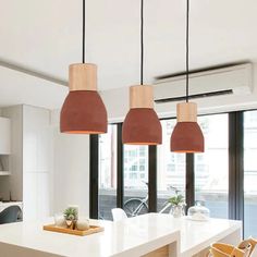 a kitchen with three pendant lights hanging from the ceiling and two chairs on the counter