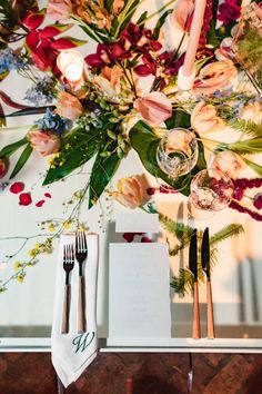 the table is set with silverware and flowers