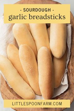 some breadsticks sitting on top of a wooden plate with the words, sourdough garlic breadsticks