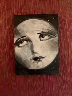 a painting of a woman's face on a wooden surface