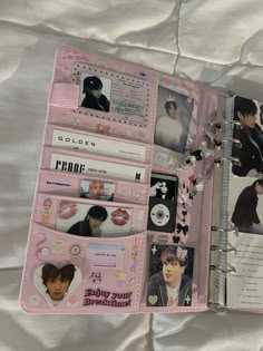 an open pink planner book with photos and pictures on it, sitting on a bed