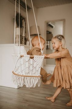 two children playing on a swing in a room