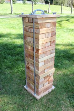 a wooden tower made out of wood blocks in the grass with a hose attached to it