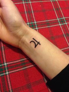 a person's wrist with a small tattoo on it, which has the letter k in cursive writing