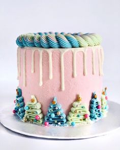 a pink cake with icing and decorated christmas trees