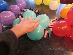 a person reaching for balloons on a table