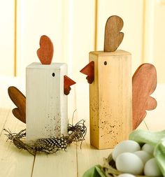 two wooden chickens sitting next to each other on top of a table