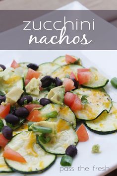 zucchini nachos with black olives and tomatoes on a white plate