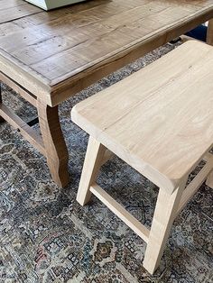 a wooden table sitting on top of a rug next to a green box and chair