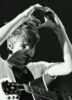 a young man holding a guitar while wearing a neck tie and headphones on his ears