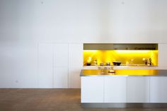 a modern kitchen with yellow lighting in the wall and counter tops on both sides, along with white cabinets