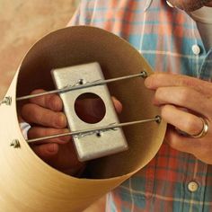 a man holding a metal object in his right hand and looking at it through the hole