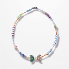 a necklace with beads and charms on it's end is shown in the shape of a bird