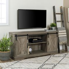 a flat screen tv sitting on top of a wooden entertainment center in a living room