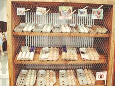 an assortment of eggs are on display in a wooden case with wire mesh dividers