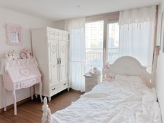 a bedroom with white furniture and pink accessories on the bed, dressers and window