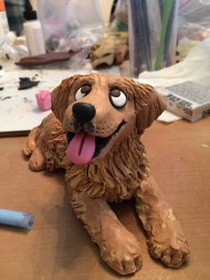 a brown dog sitting on top of a wooden table next to a blue pen and paper