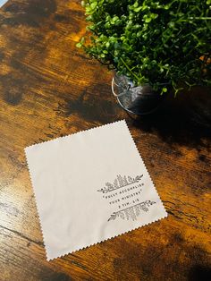 a napkin sitting on top of a wooden table next to a potted plant