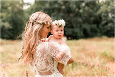 a woman holding a baby in her arms and wearing a flower crown on her head