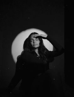 a black and white photo of a woman holding her hair in front of the moon