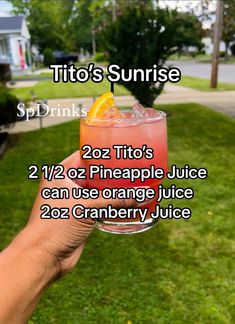 a person holding up a drink in their hand with the words tito's sunrise on it