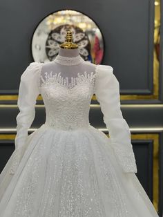 a white wedding dress on display in front of a clock