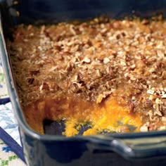 a blue casserole dish filled with food on top of a white and blue cloth