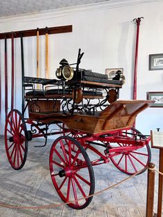 an old fashioned carriage is on display in a museum room with red wheels and spokes