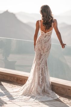 the back of a woman's dress as she stands on a balcony overlooking mountains