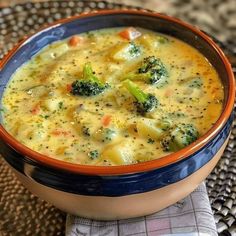 a bowl of soup with broccoli and carrots in it on a table