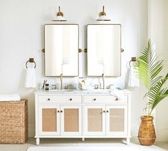 a white bathroom with two mirrors above the sinks and a wicker basket on the floor