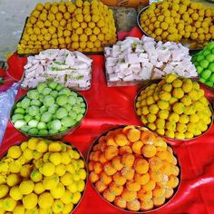 several bowls filled with different types of fruit on display at an outdoor vendor's market