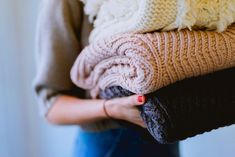 a woman holding several blankets in her hands