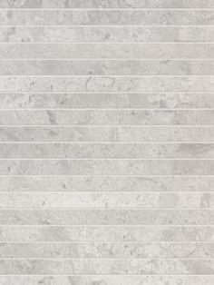 a white marble tile wall with vertical lines in the center and diagonals on each side