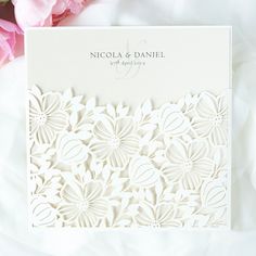 a wedding card with white paper cut flowers on it and the words, nicholas & danielle