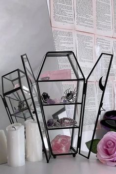 three glass shelves with candles and flowers in front of an open book