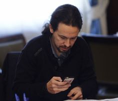 a man looking at his cell phone while sitting at a table in front of him