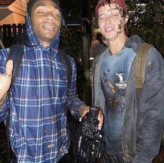 two men standing next to each other with mud all over their face and one holding a camera