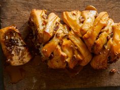 some food is sitting on top of a wooden cutting board and drizzled with caramel sauce