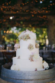 a white wedding cake sitting on top of a barrel