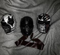 three different types of skull helmets on a bed with a satin ribbon tied around them