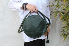 A round or circular purse made of genuine leather in emerald green with a front pocket (not suitable for phone) detachable long cross body strap, handheld grab top handle, can be worn in hand or shoulder or across the body so very versatile.  Such a cute gorgeous bag in the most beautiful colour green.   MEASUREMENTS  Diameter 24 cm x 7 Width Front pocket 24 cm x 13.5 Internal pocket 12.5 x 11.5 deep Zip pocket 15 x 15 deep Strap 2cm x 68cm ( 136 max ) Green Shoulder Bag With Round Handle For Everyday, Green Bag With Round Handle For Everyday Use, Green Formal Bags With Round Handle, Formal Green Bags With Round Handle, Everyday Green Shoulder Bag With Round Handle, Green Shoulder Bag With Detachable Strap And Round Handle, Green Bag With Detachable Strap And Round Handle, Green Leather Shoulder Bag With Round Handle, Round Purse