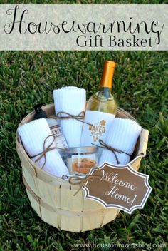 a basket filled with towels and bottles of wine on top of green grass next to a sign that says housewarming gift basket