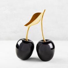 two black and gold cherries with a leaf sticking out of it's top