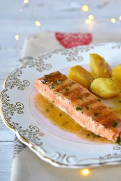 a plate topped with salmon and potatoes on top of a table