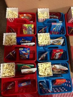 several trays filled with snacks on top of a table next to a box full of popcorn