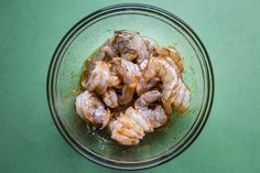 a glass bowl filled with shrimp on top of a green table