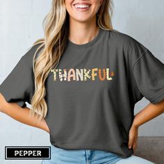 A fall-themed t-shirt with the word Thankful in a unique font, adorned with autumn leaves in warm colors. Perfect for individuals who want to express gratitude during the autumn season or Thanksgiving celebrations. Product features - Comfort Colors 1717 tee - Available in sizes S to 4XL for the perfect fit - Double-needle stitching for durability - Without side seams for a more attractive look - Garment-dyed fabric for soft color and texture - Made with high quality 100% ring-spun US cotton for comfort - It has a relaxed fit and the pre-shrunk fabric ensures a consistently great fit. Check the size chart for your best fit. ❤️ Care Instruction: - Machine wash: cold (max 30C or 90F) - Do not bleach - Tumble dry: low heat - Iron, steam or dry: low heat - Do not dryclean 💙 Return & Exchanges: Fall Short Sleeve T-shirt With Text Print, Fall Relaxed Fit T-shirt With Text Print, Cotton Crew Neck T-shirt For Thanksgiving, Casual Thanksgiving Graphic Print T-shirt, Thanksgiving Cotton Graphic Print T-shirt, Unique Font, Express Gratitude, Pumpkin Spice Season, Festival Clothing